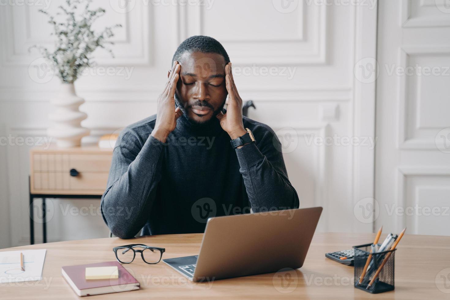 concerné jeune employé afro-américain souffrant de maux de tête sur le lieu de travail photo