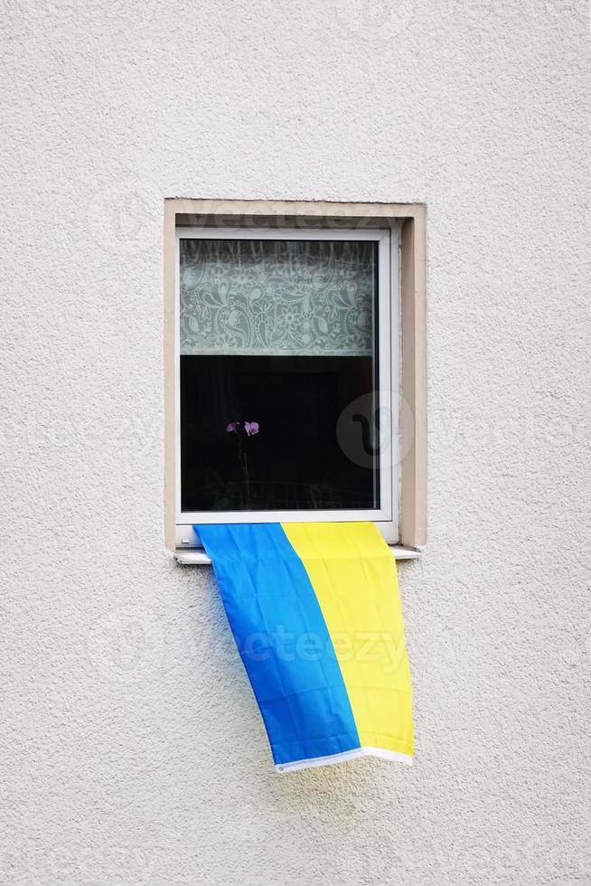 drapeau de l'ukraine accroché à la fenêtre d'un immeuble résidentiel photo