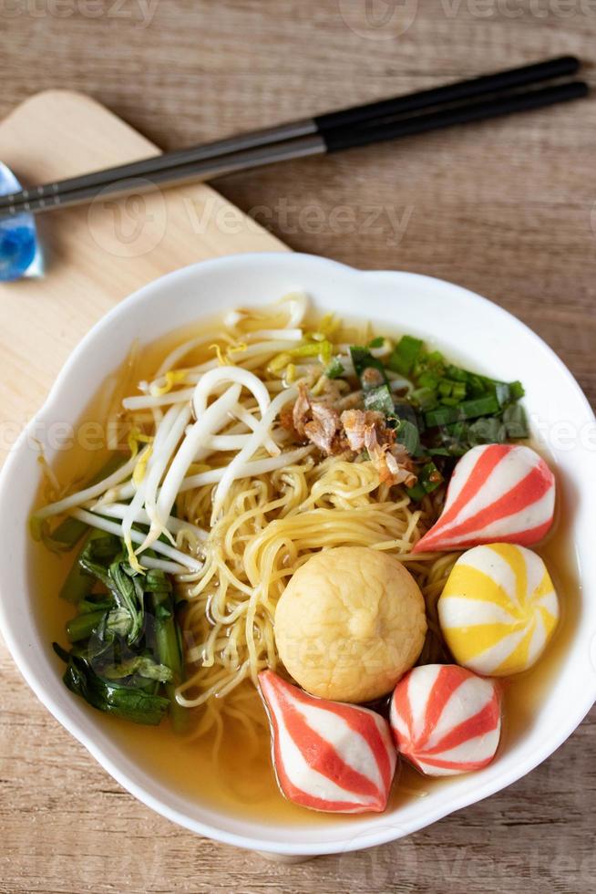 nouilles aux œufs avec des boulettes de poisson colorées japonaises dans une tasse blanche photo