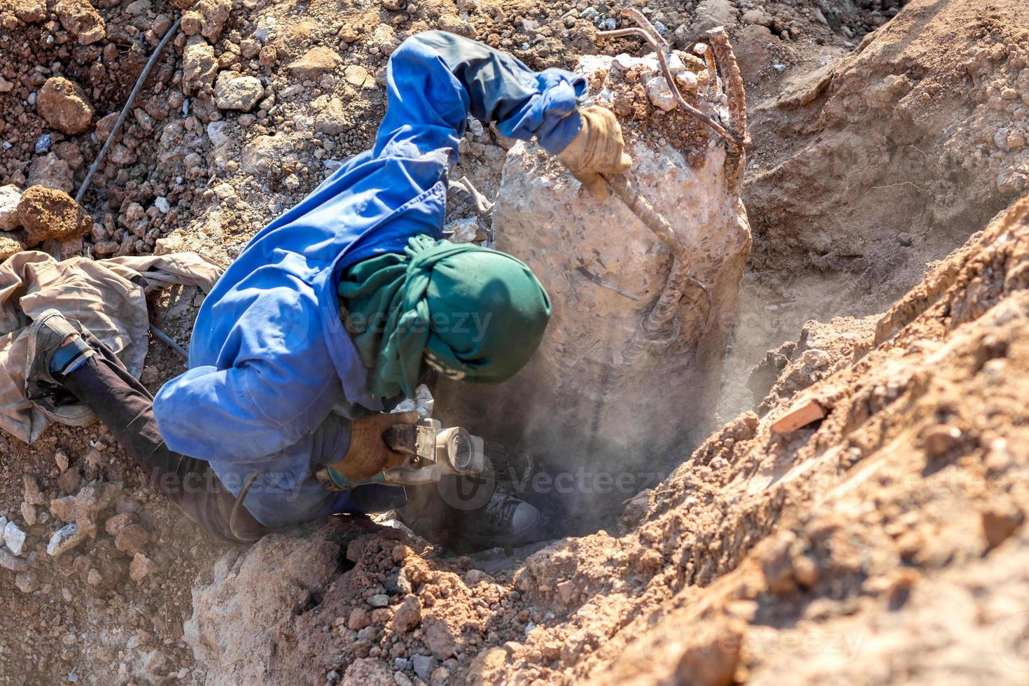 un travailleur avec une perceuse à percussion a heurté le poteau en béton. photo