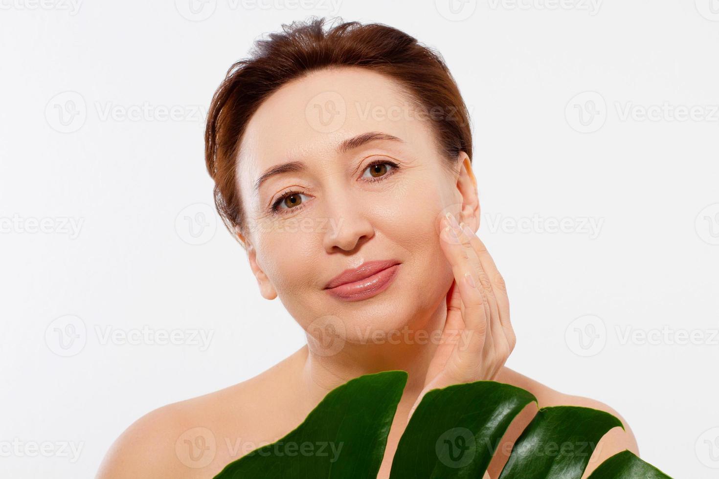 portrait de visage macro de femme d'âge moyen de beauté. spa et concept anti-vieillissement et feuille isolé sur fond blanc. chirurgie plastique et injections de collagène pour le visage. rides et ménopause. maquette. espace de copie. photo