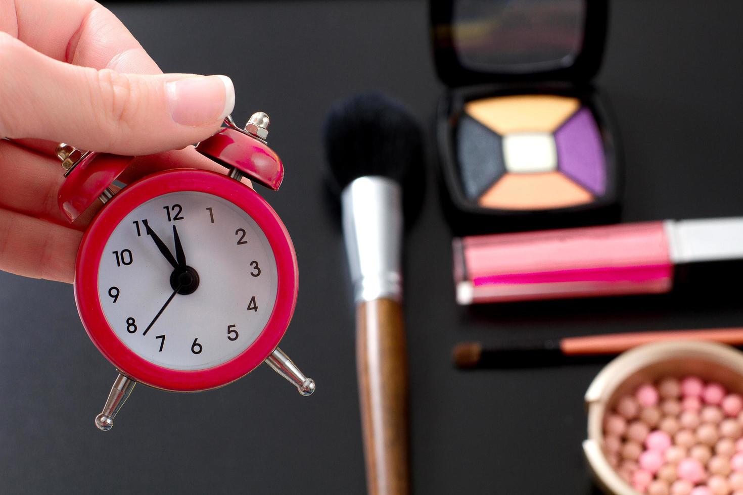 concept image recadrée avec des produits cosmétiques et de maquillage. maquillage rapide. horloge rétro rouge. mise au point sélective photo