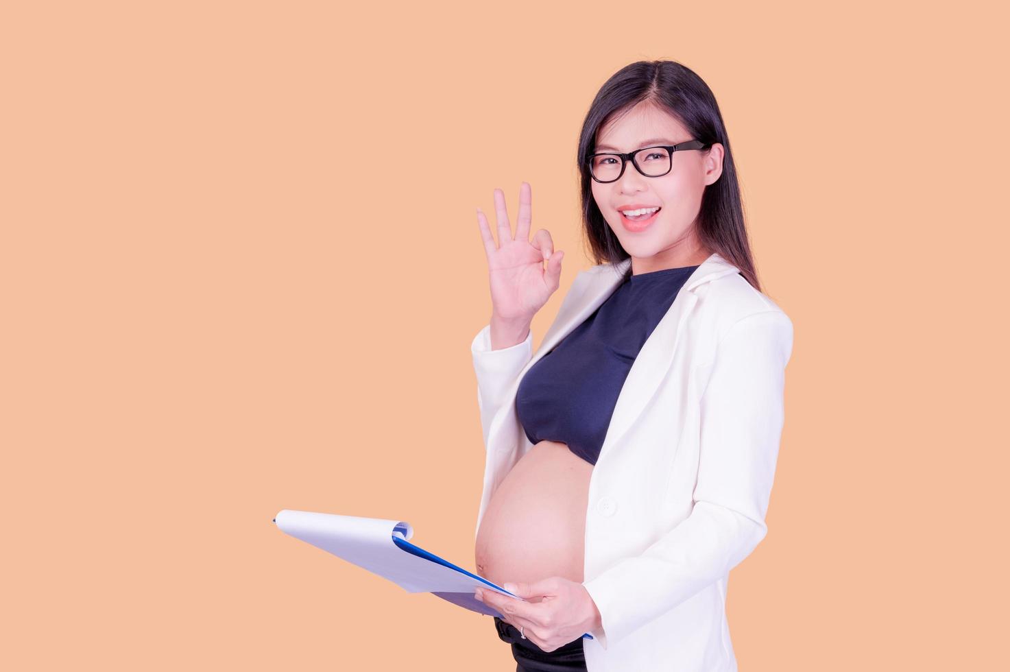 une belle femme asiatique enceinte tenant un classeur en papier, se détendant et appréciant son travail photo