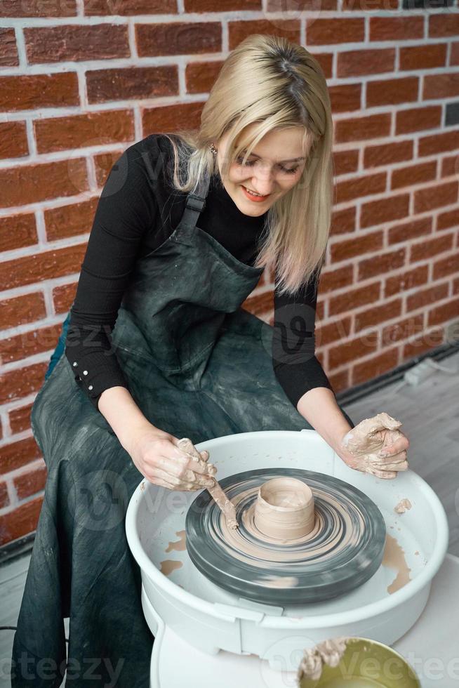 femme heureuse souriante faisant de la poterie en céramique sur roue. concept pour femme en freelance, entreprise. produit artisanal. gagner de l'argent supplémentaire, faire de l'agitation secondaire, transformer les loisirs en argent et la passion en travail photo