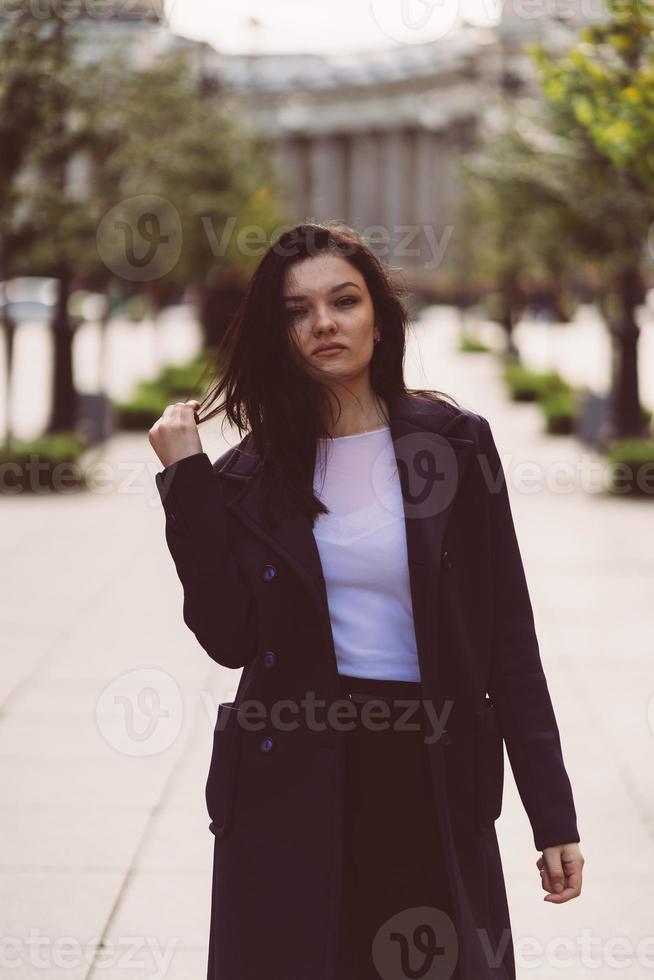 belle fille brune intelligente sérieuse marchant dans la rue de st. Saint-Pétersbourg dans le centre-ville. charmante femme réfléchie aux longs cheveux noirs erre seule photo