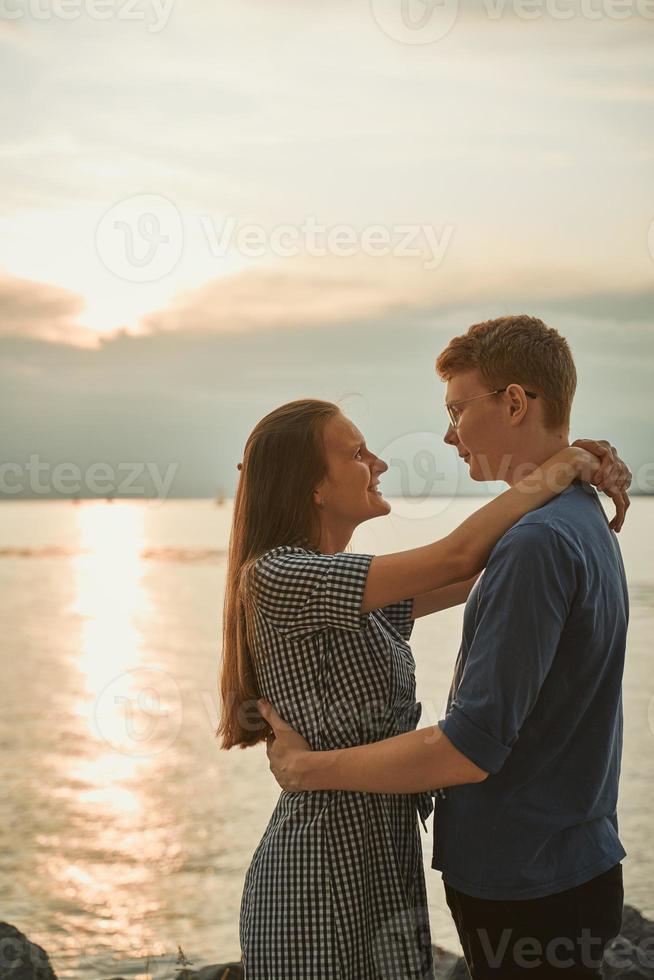 les partenaires amoureux se regardent sur la plage, le temps nuageux et le coucher du soleil sur fond photo