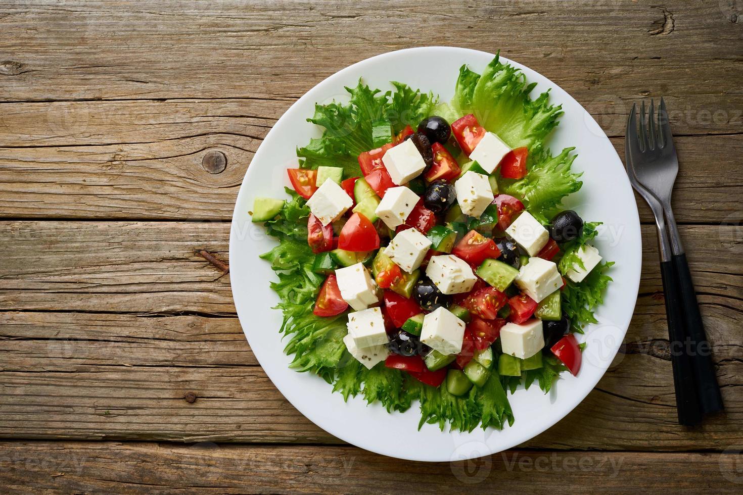 salade grecque sur une assiette blanche sur une vieille table en bois rustique, vue de dessus, espace de copie photo
