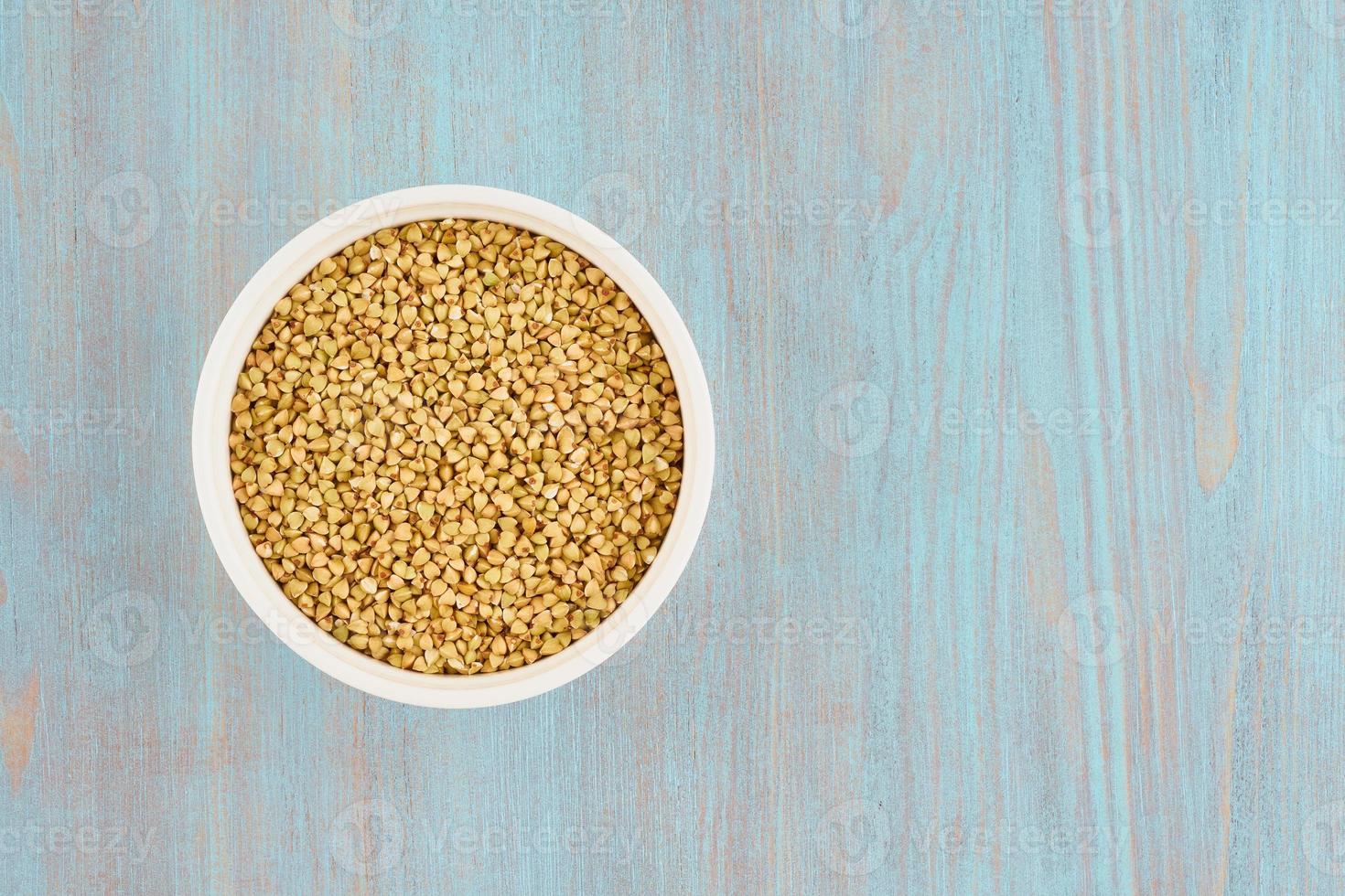 sarrasin vert dans un bol blanc sur une table en bois bleue, grains entiers sans gluten, régime fodmap photo