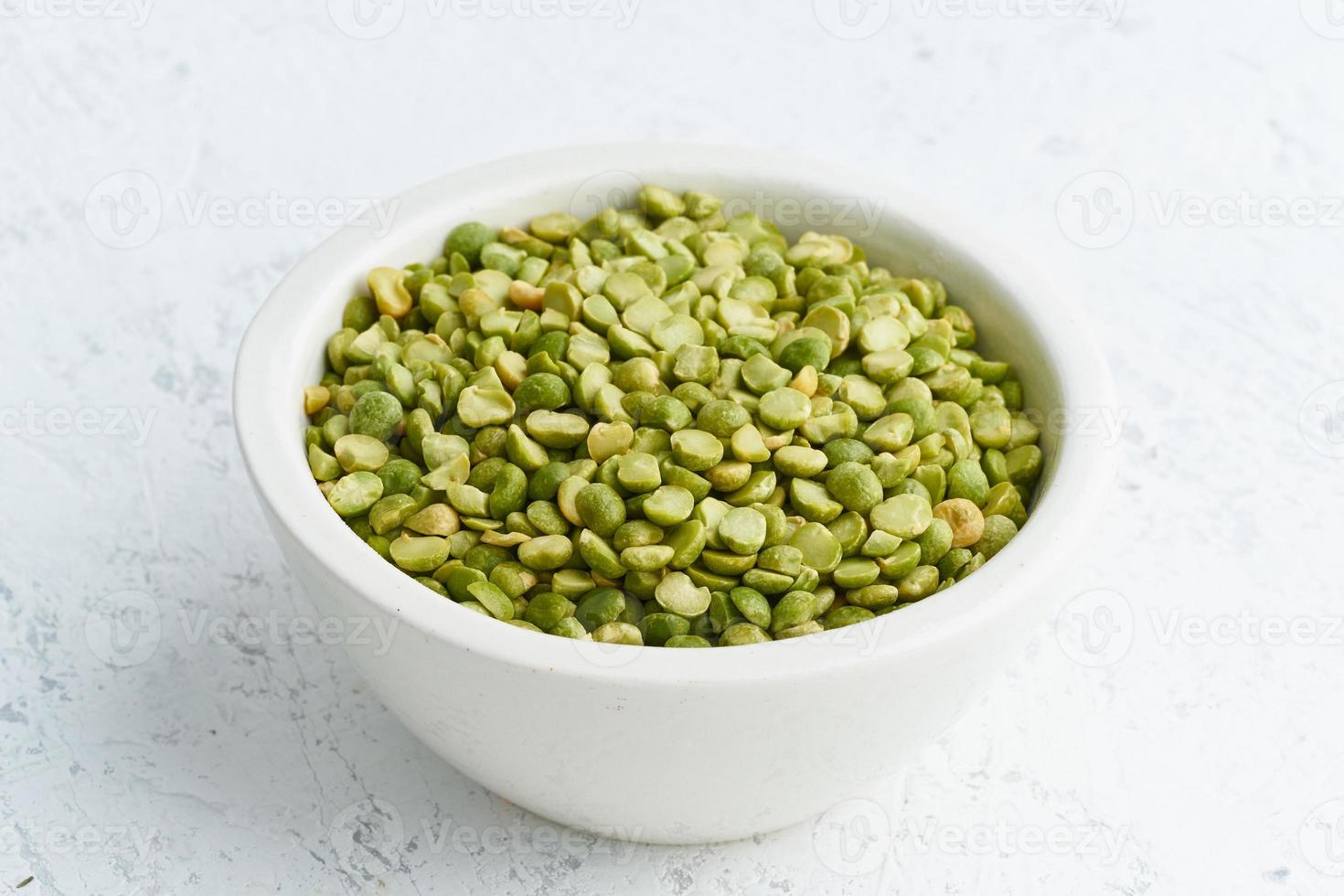 pois verts dans un bol blanc sur fond blanc. céréales séchées en tasse, nourriture végétalienne. vue de côté photo