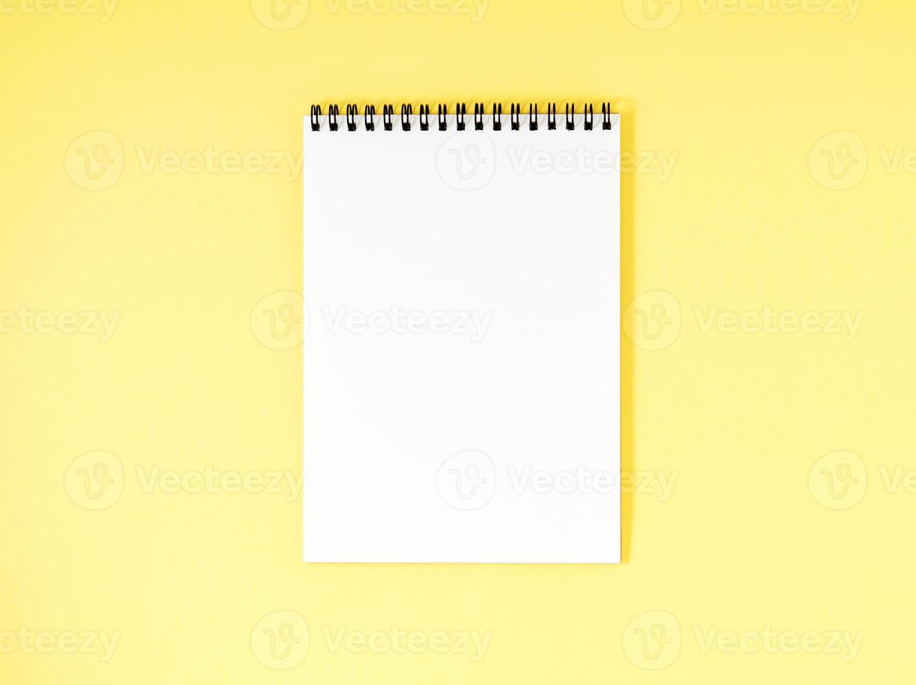 bloc-notes vierge page blanche sur le bureau jaune, fond de couleur. vue de dessus, espace vide pour le texte. photo