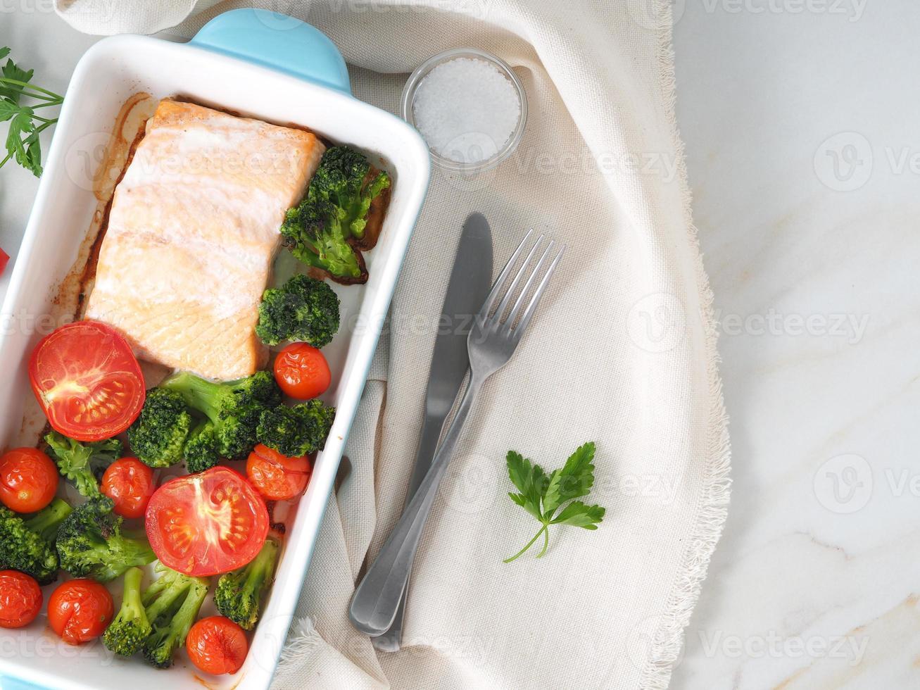 saumon de poisson cuit au four avec légumes, brocoli. régime alimentaire sain, toile de fond en marbre blanc, vue de dessus, gros plan photo