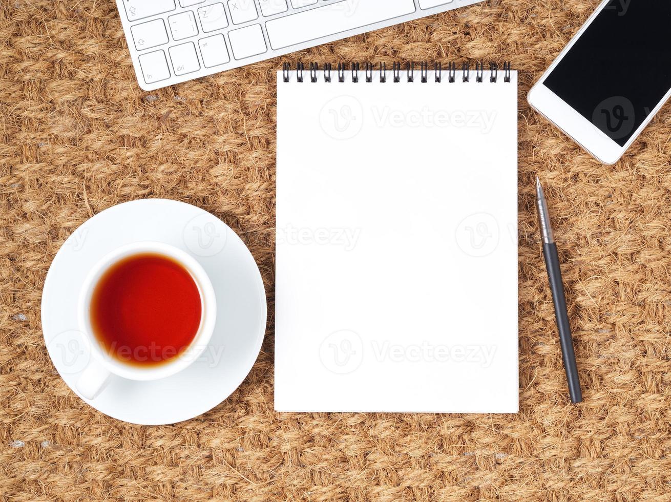 lieu de travail avec ordinateur portable et bloc-notes vierge sur tapis. vue de dessus. mise à plat. bureau indépendant, climat chaud photo