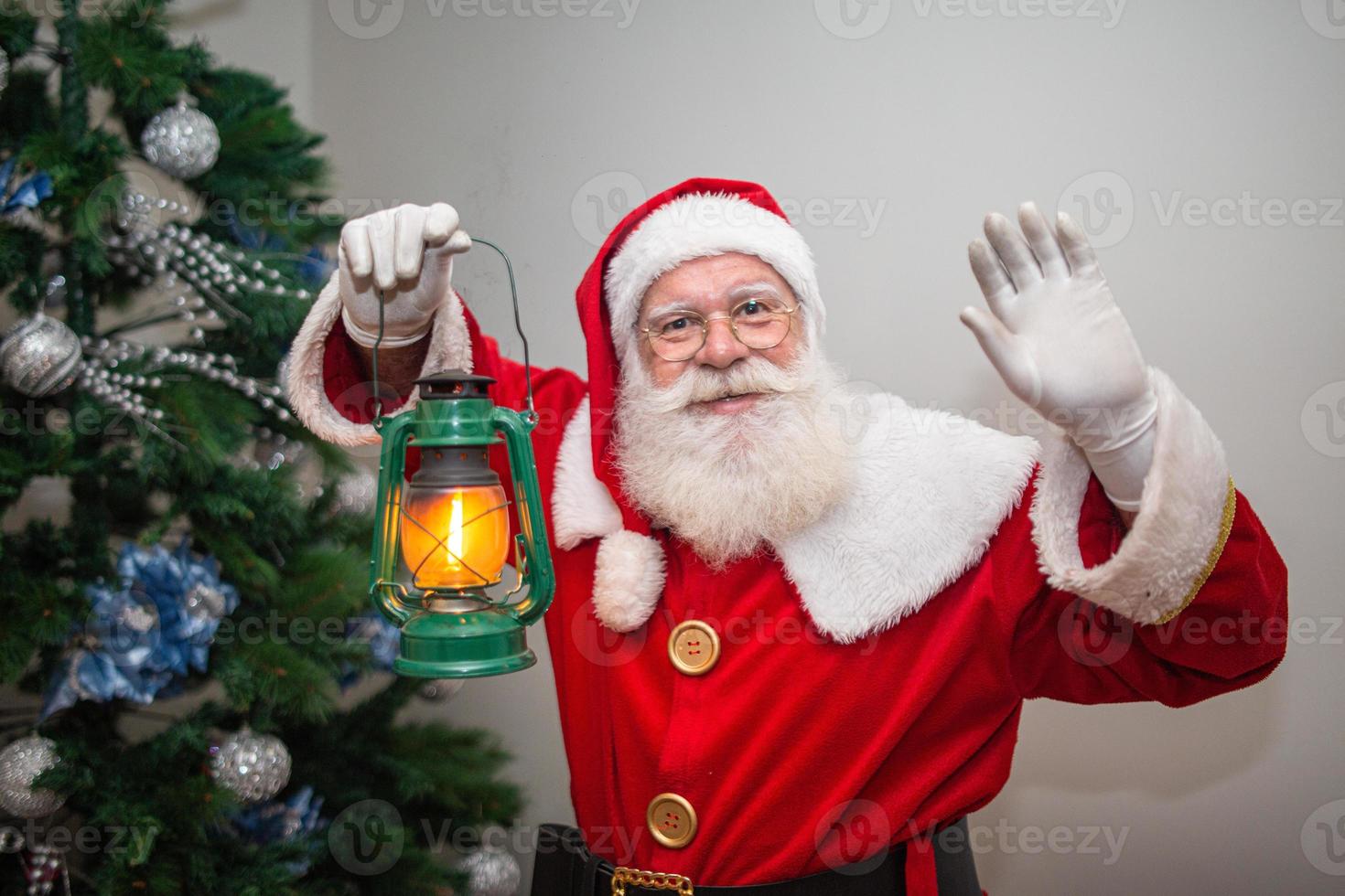 le père noël tenant une lampe qui se tait dans une maison. livraison de cadeaux de noël. le père noël se faufile pour laisser les cadeaux. photo