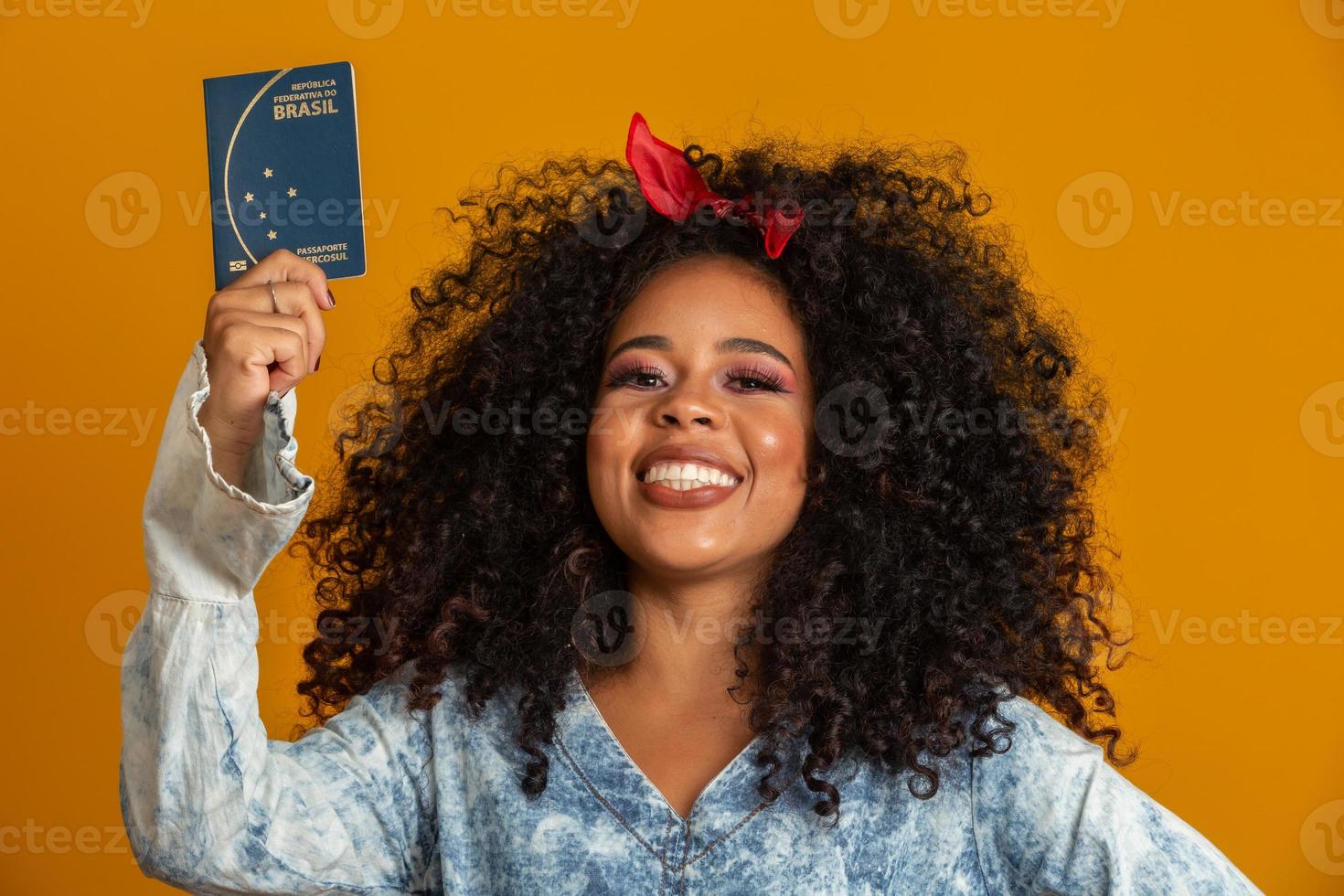 belle fille aux cheveux bouclés en voyage. prochain voyage. fille tenant un passeport brésilien. photo