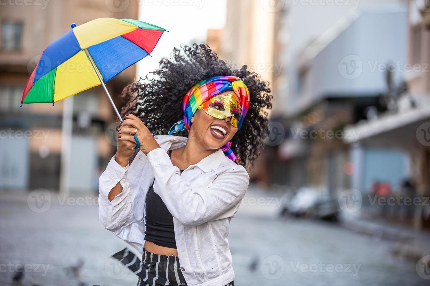 jeune femme aux cheveux bouclés célébrant la fête du carnaval brésilien avec un parapluie frevo dans la rue. photo