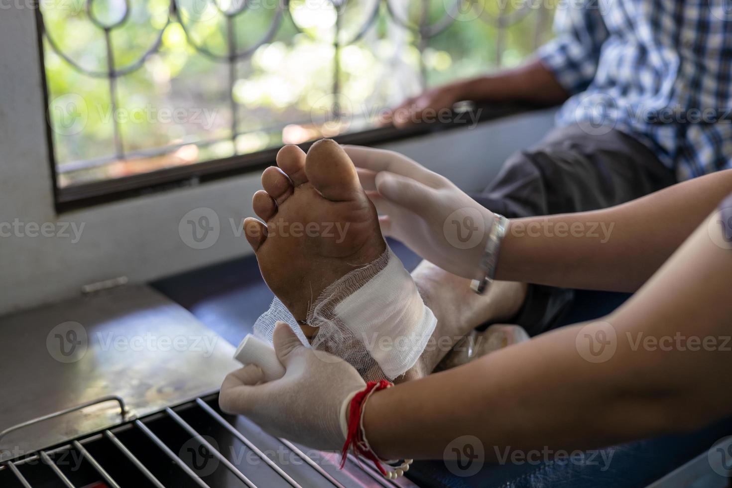 une infirmière applique un bandage sur un pied âgé. photo