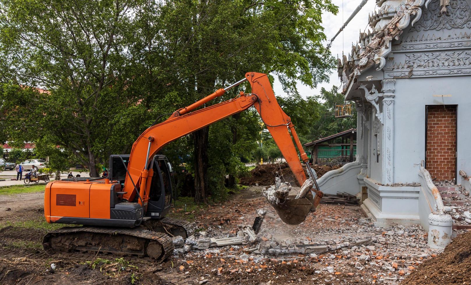 rétrocaveuse orange pour démanteler le crématorium en ciment. photo