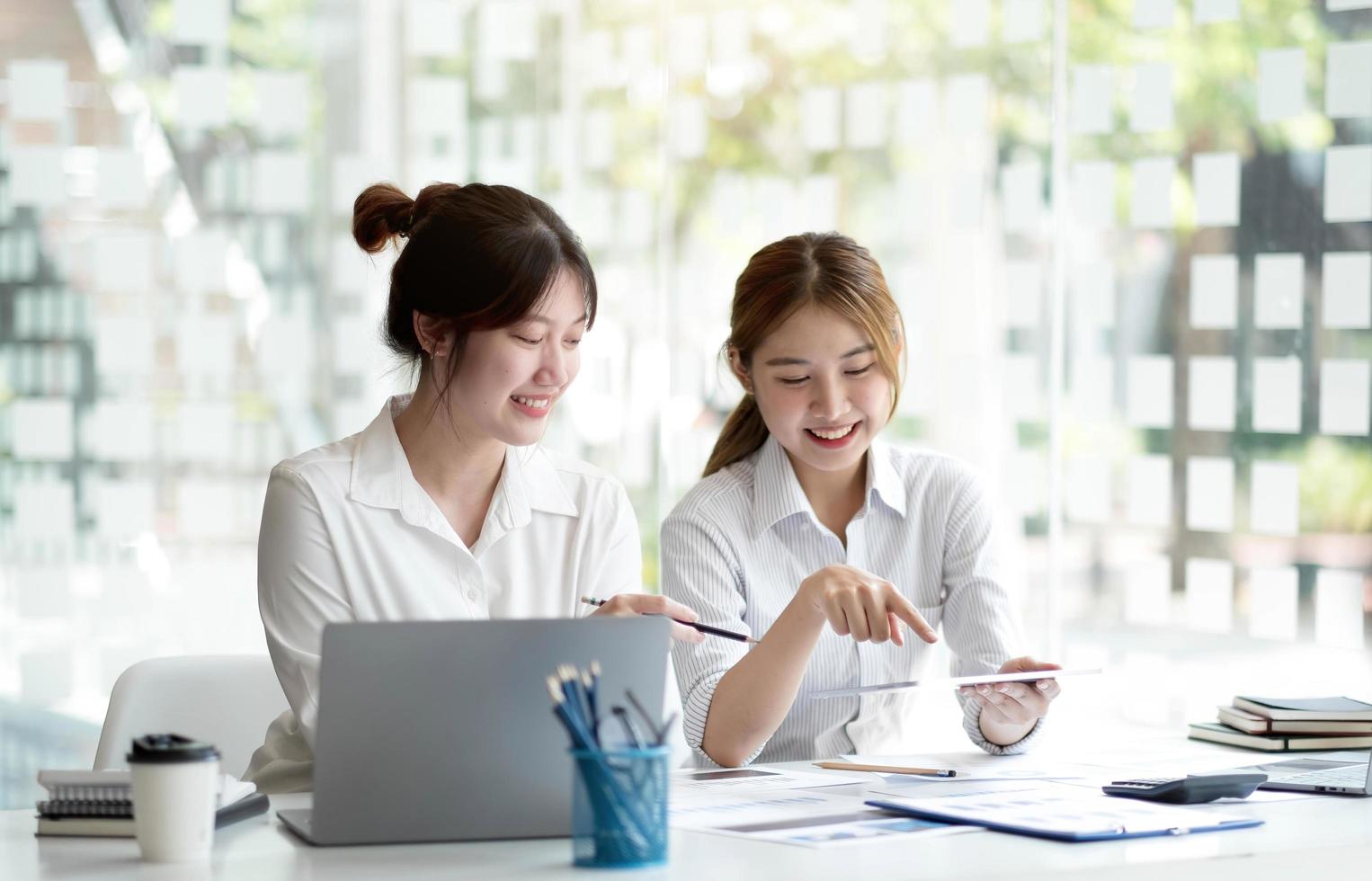 deux jeunes femmes d'affaires asiatiques discutent avec la présentation d'une nouvelle idée de projet de démarrage, analysent la planification et les statistiques financières et le marché de l'investissement au bureau. photo