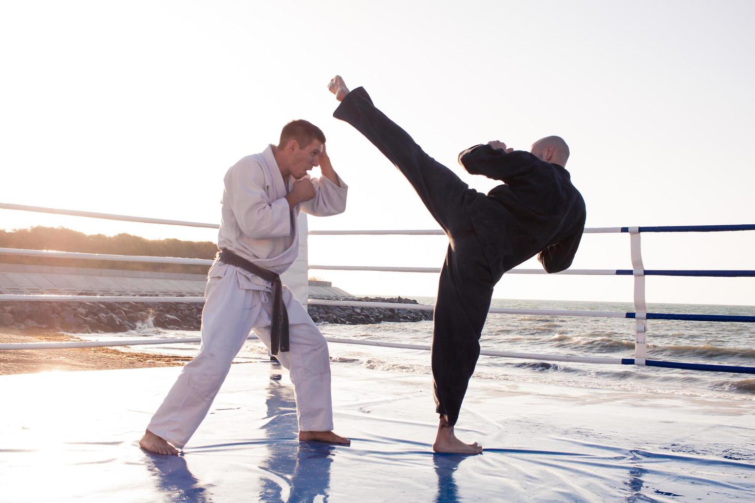 les combattants de karaté se battent sur le ring de boxe de la plage le matin photo