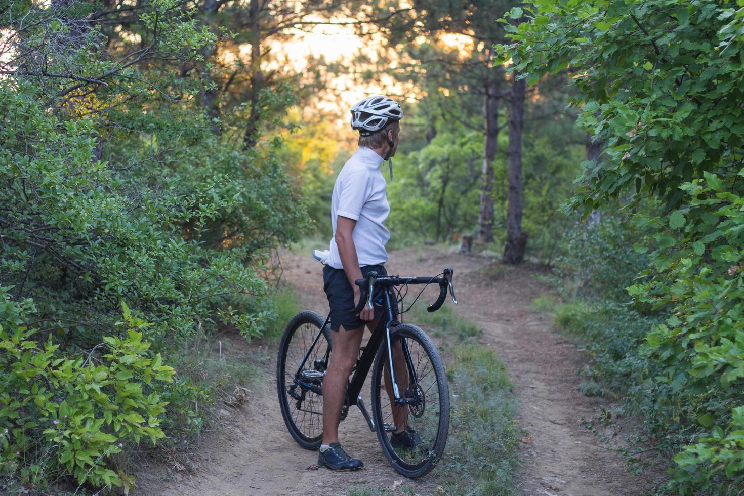 jeune athlète à cheval sur son vélo professionnel de montagne ou de cyclocross dans la forêt photo