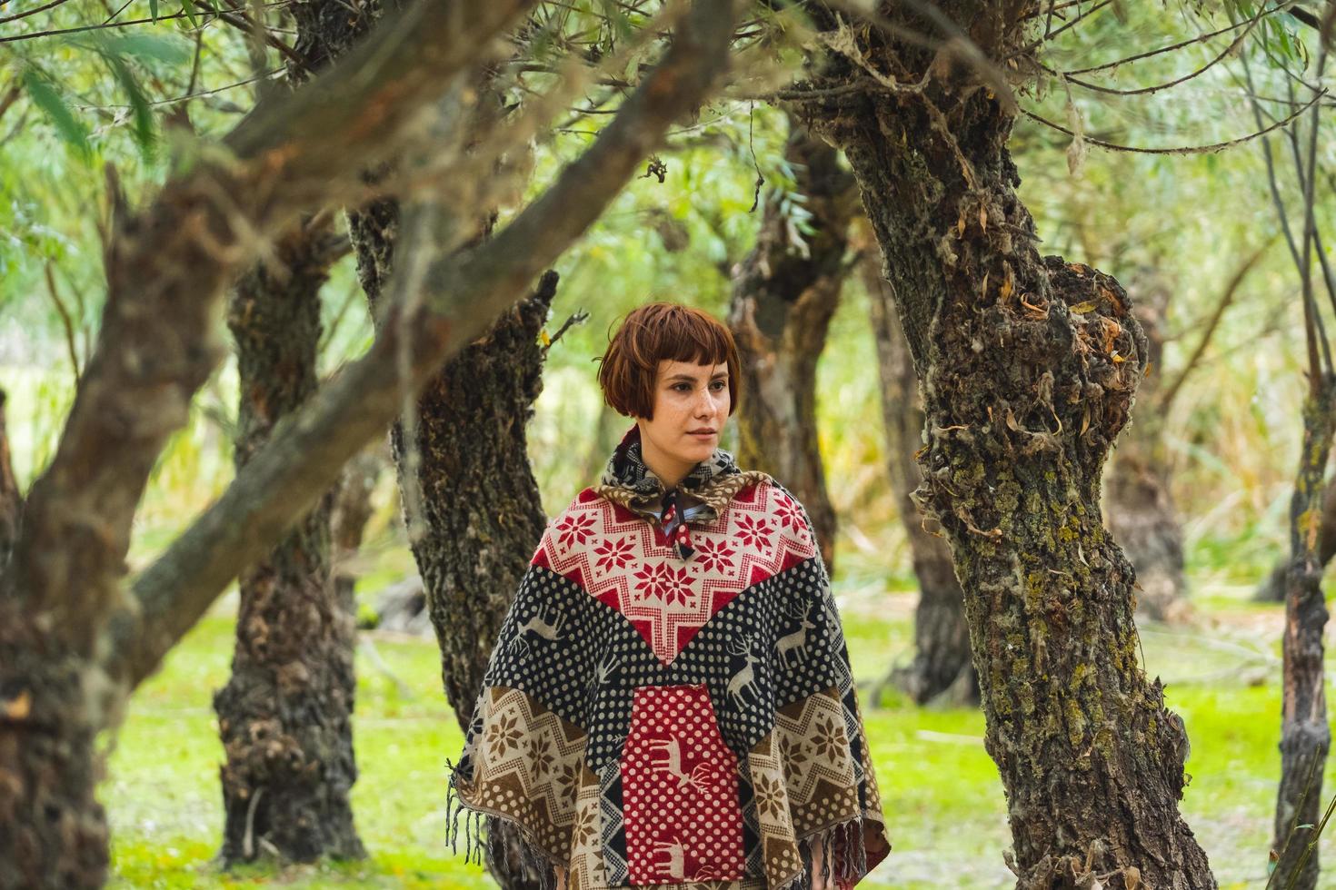 jeune femme voyageuse vêtue d'un poncho à pied à l'extérieur dans les champs d'automne photo