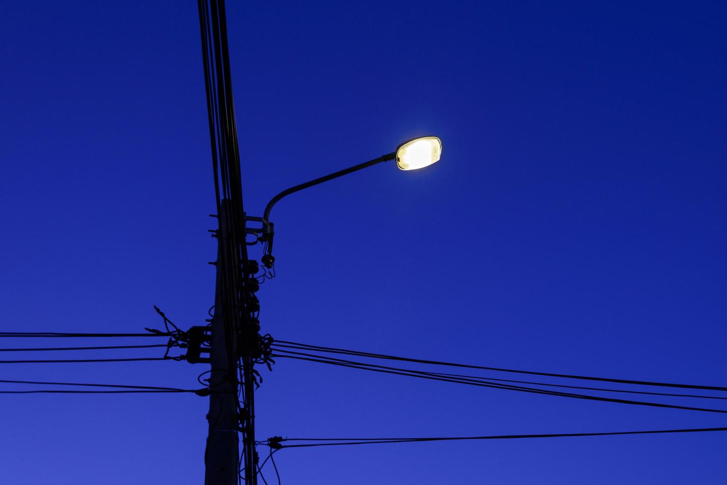 poteau électrique et ligne de câble avec réverbère la nuit photo