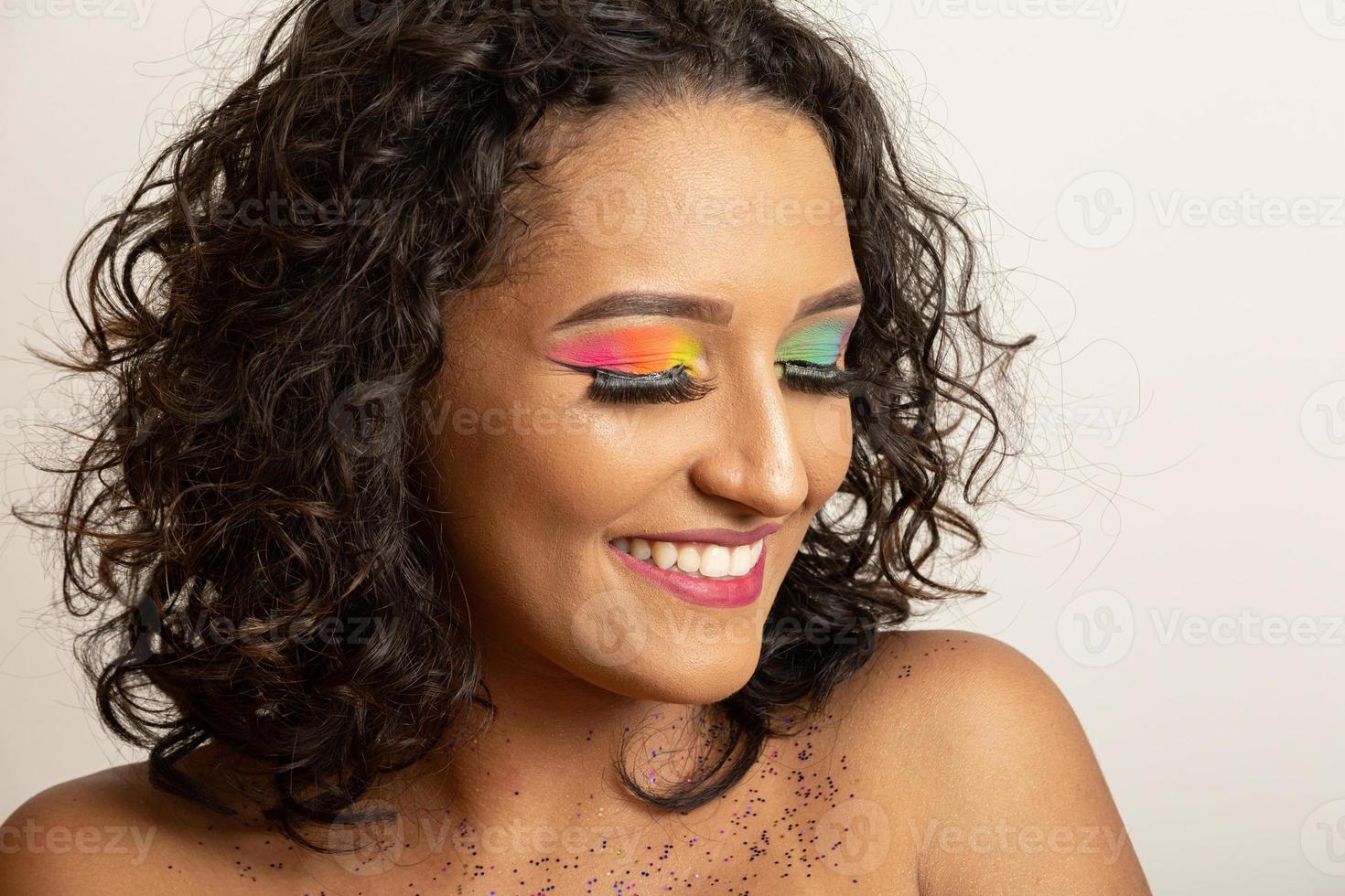 beauté mannequin fille aux cheveux bouclés et maquillage coloré. femme afro souriante photo