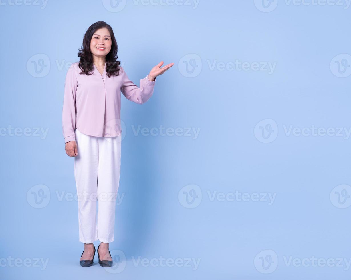 image pleine longueur d'une femme asiatique d'âge moyen sur fond bleu photo