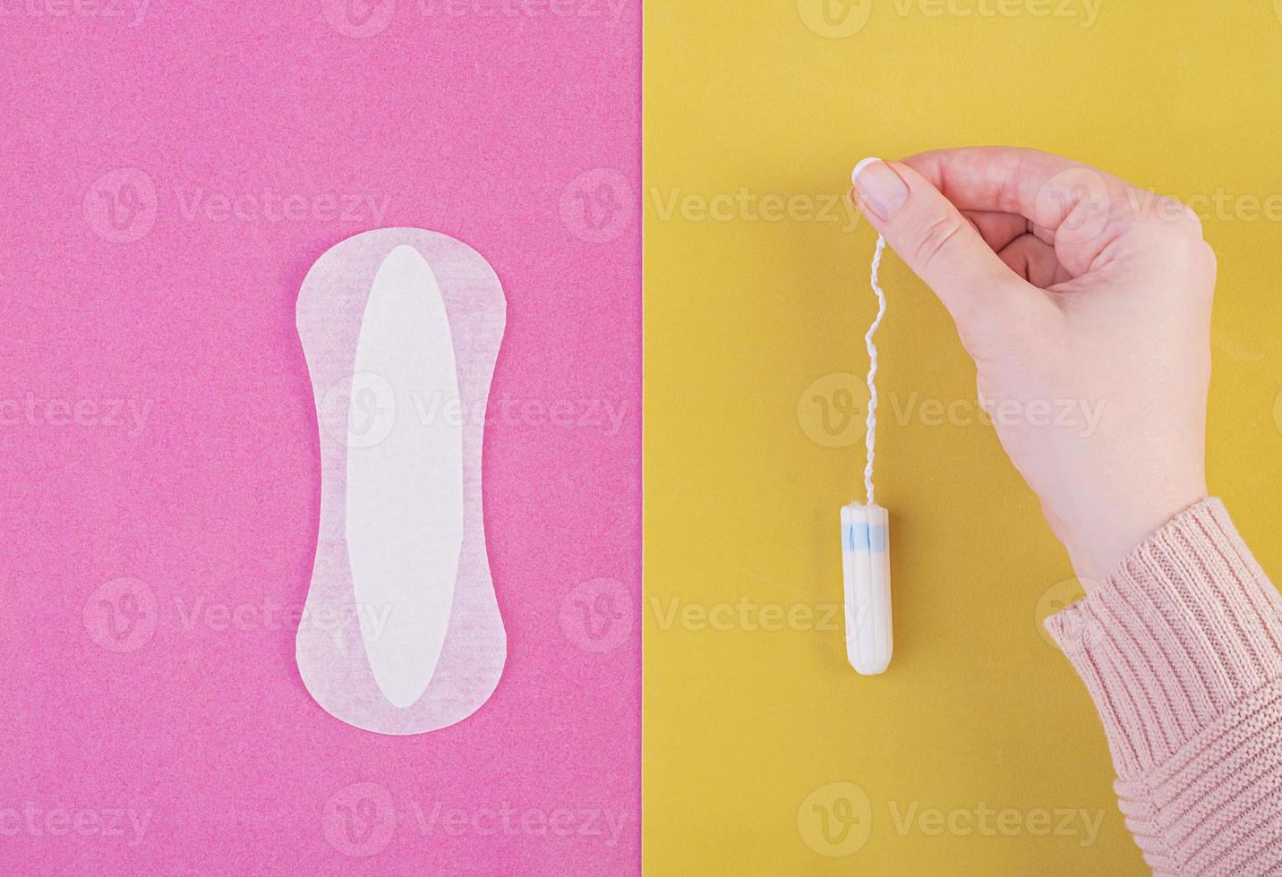 soins d'hygiène pendant les jours critiques. choisir entre un tampon et une serviette hygiénique. cycle menstruel. la femme tient dans les mains d'un tampon. vue de dessus photo