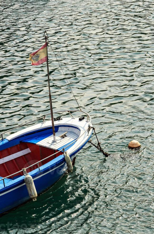 bateau bleu avec drapeau à san vicente de la barquera, cantabrie, espagne.image verticale. photo