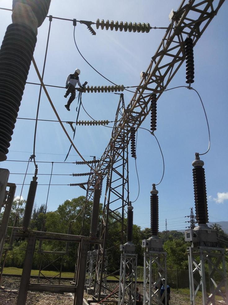 deux électriciens font des réparations et de l'entretien sur la tour électrique en hauteur photo