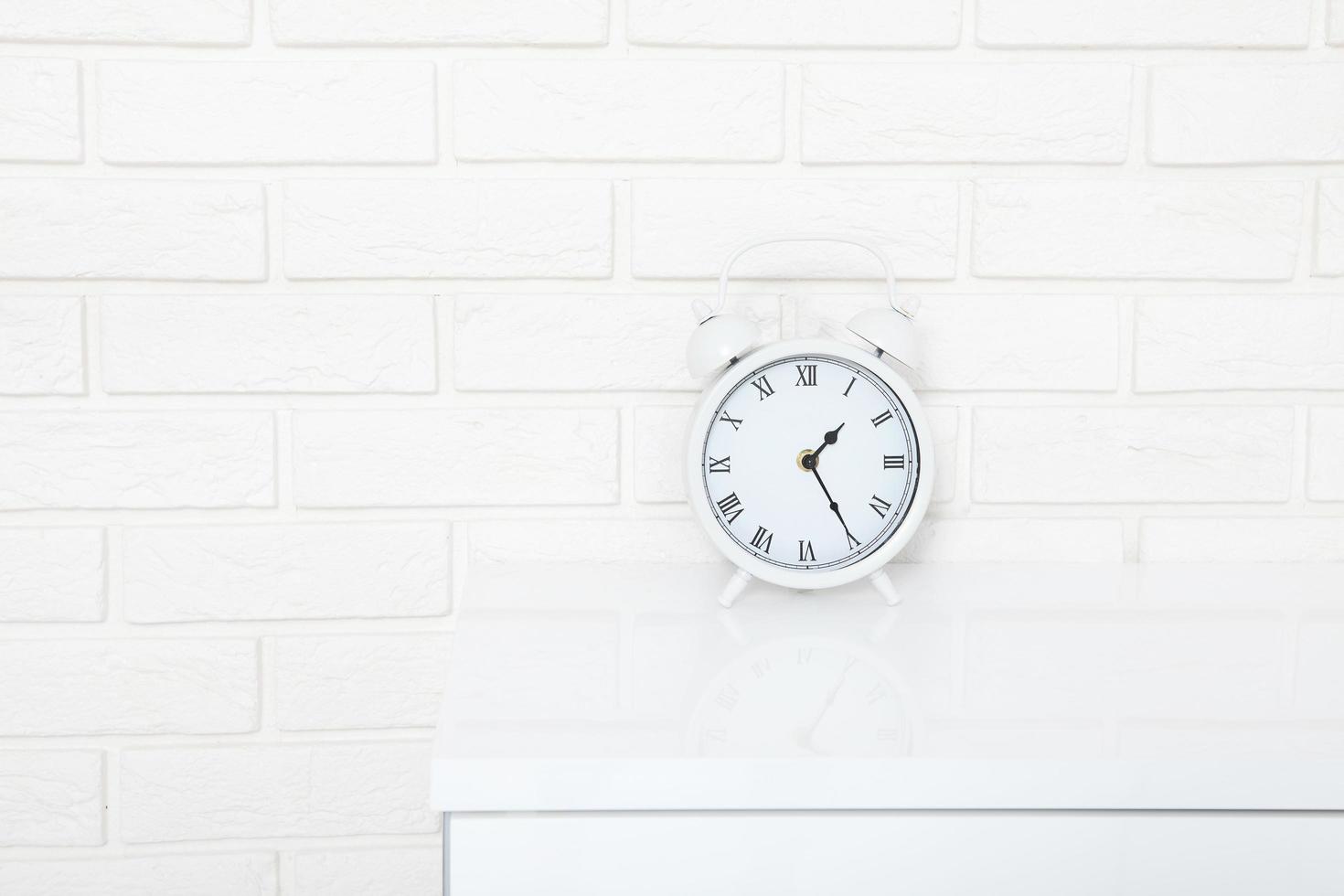 réveil rétro avec vingt-cinq minutes après une heure près du mur de briques sur le lieu de travail blanc. mise au point sélective photo