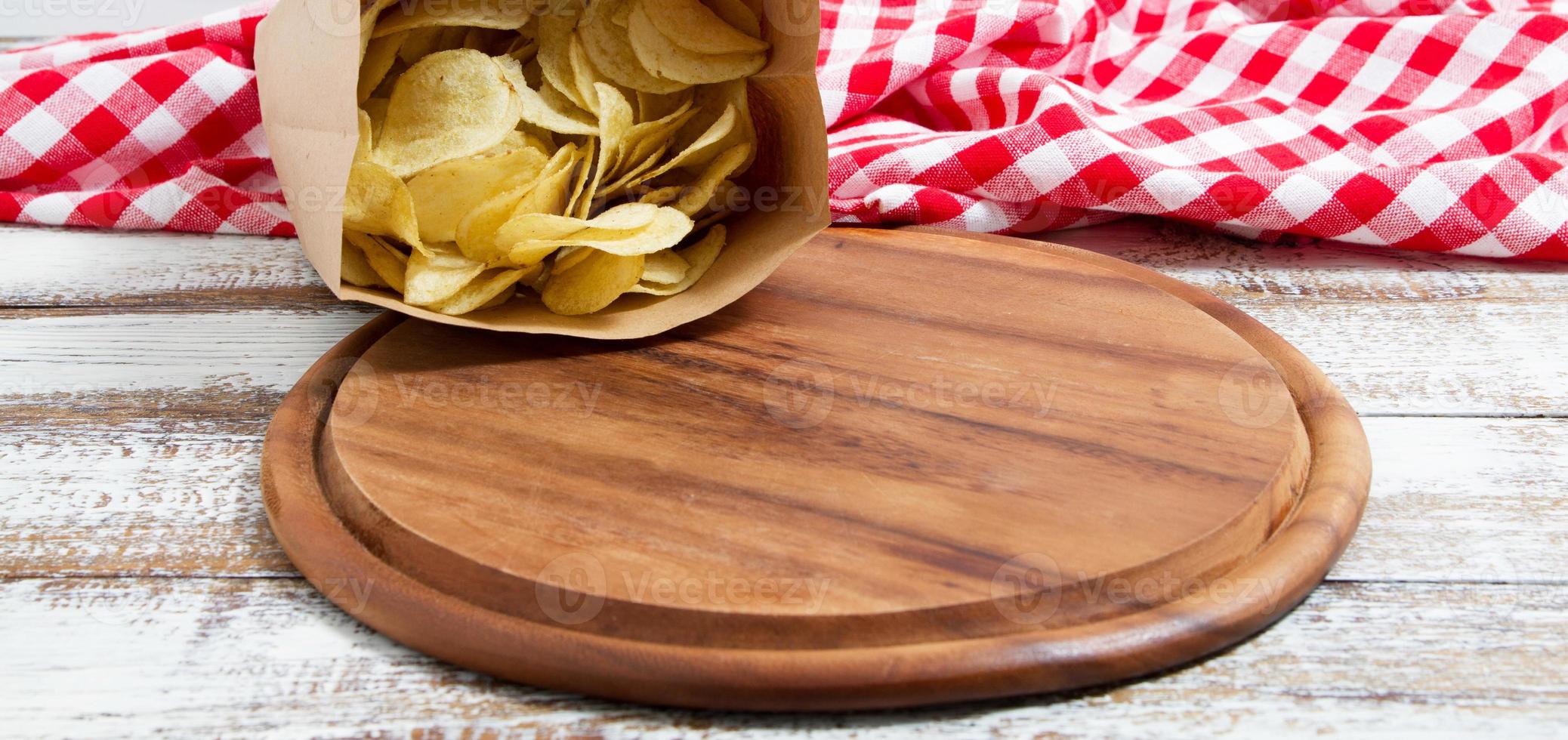 chips de pommes de terre au piment rouge épicé et plateau vide sur une table en bois photo