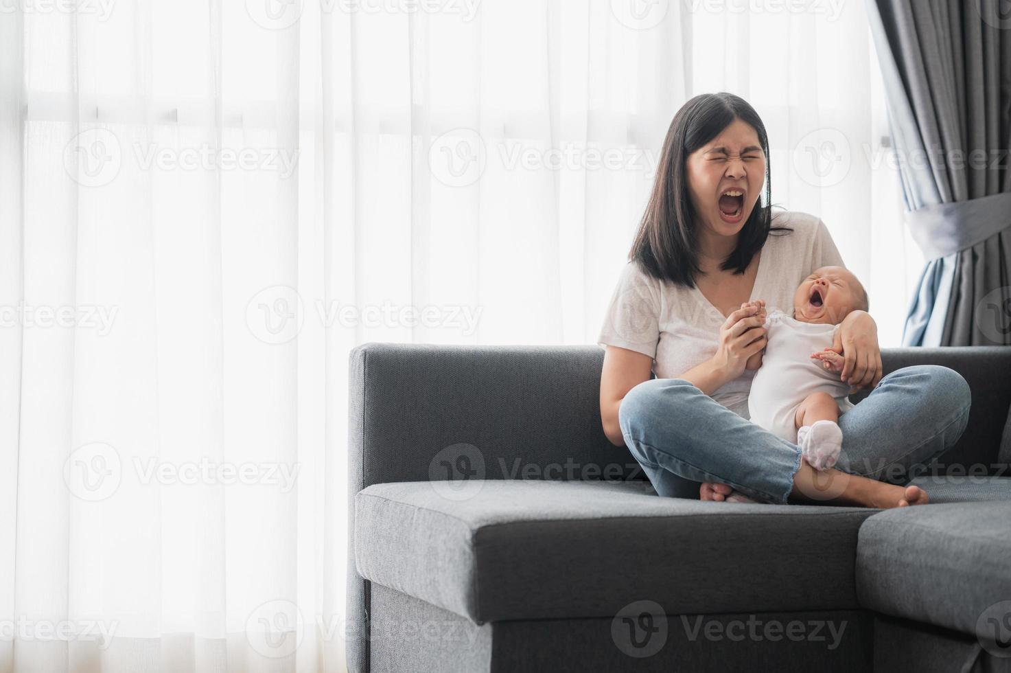 bébé bâille dans les bras de sa mère photo