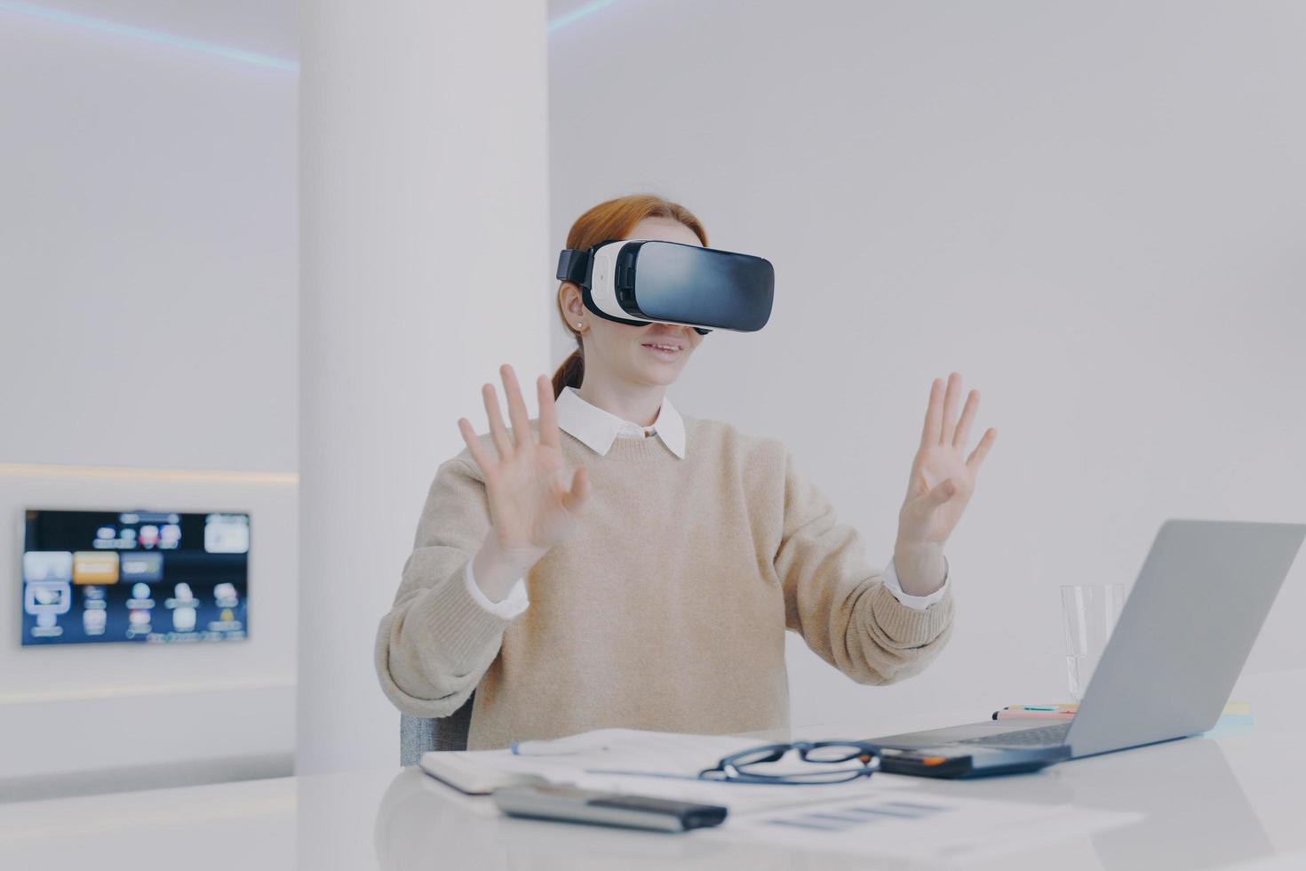 jeune femme européenne contemporaine dans un casque vr travaille au bureau. futur concept d'innovations. photo