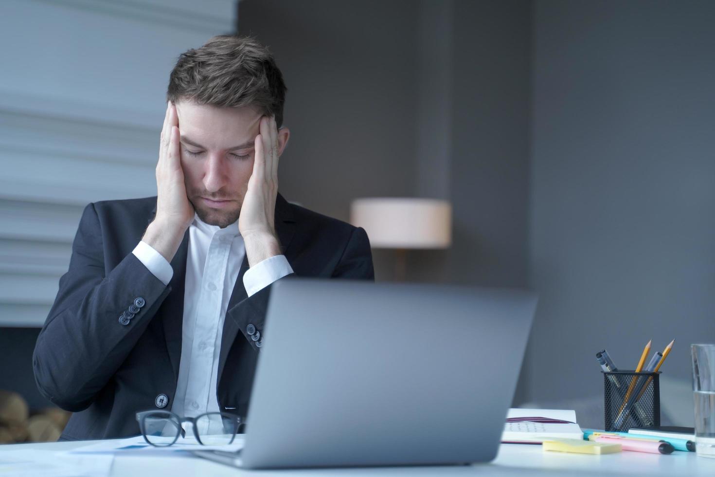 un conseiller juridique épuisé assis au bureau à domicile touche doucement ses tempes avec les doigts photo