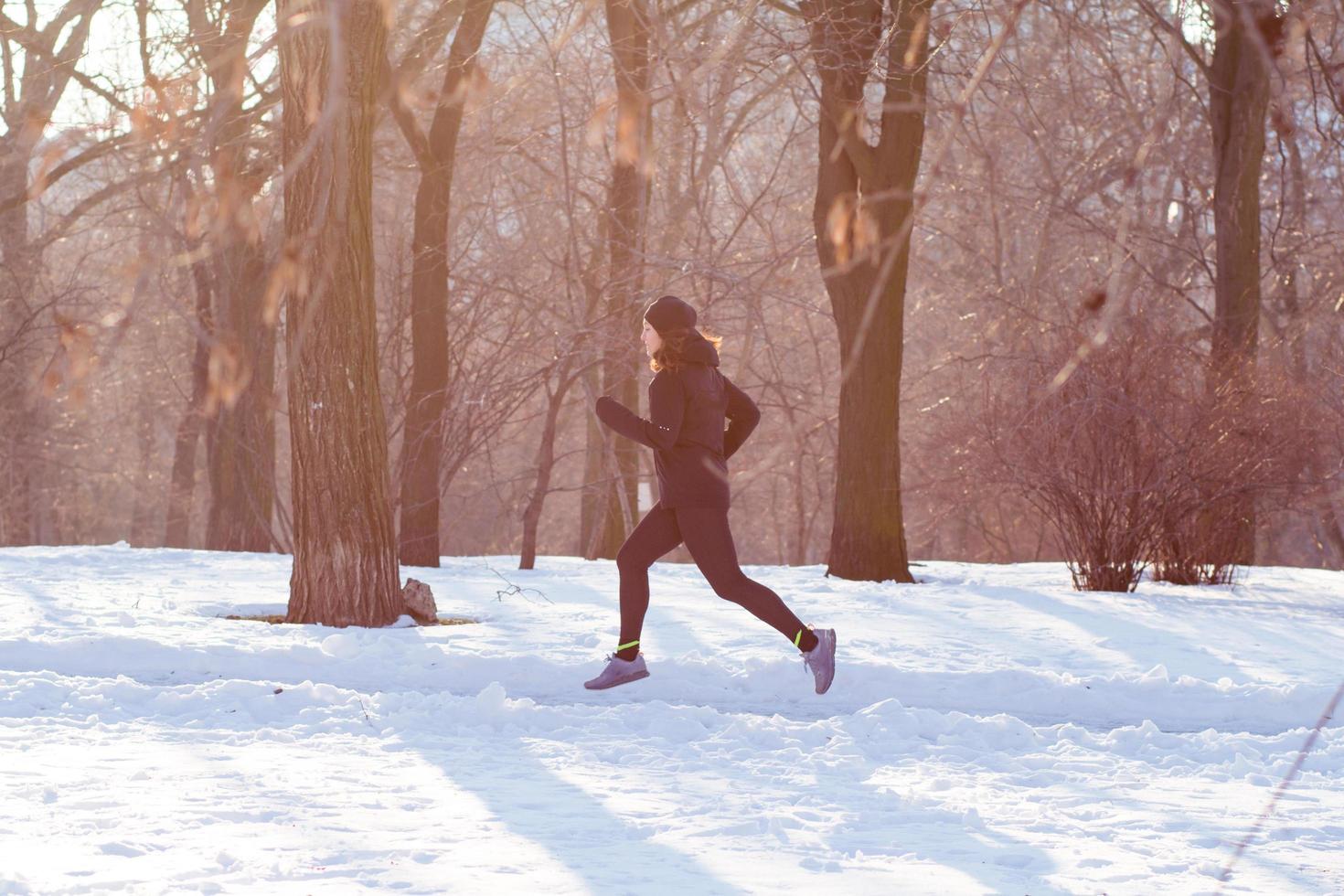 jeune femme athlète en costume de sport noir courir à winter park photo