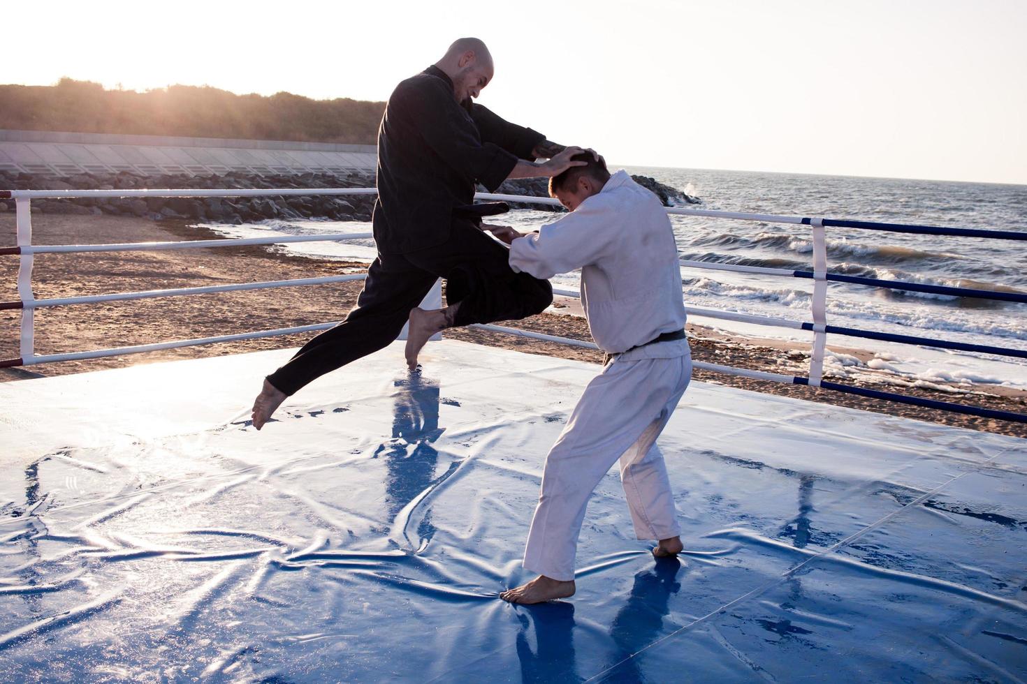 les combattants de karaté se battent sur le ring de boxe de la plage le matin photo