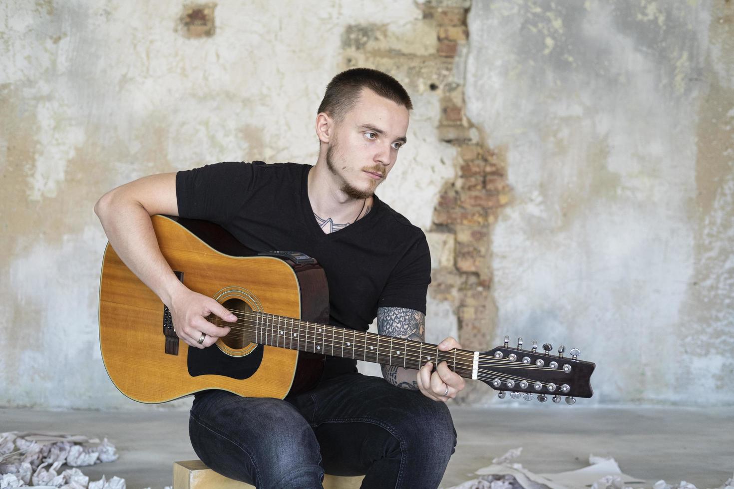 jeune homme avec guitare dans une pièce vide, musicien et auteur-compositeur seul dans le studio photo