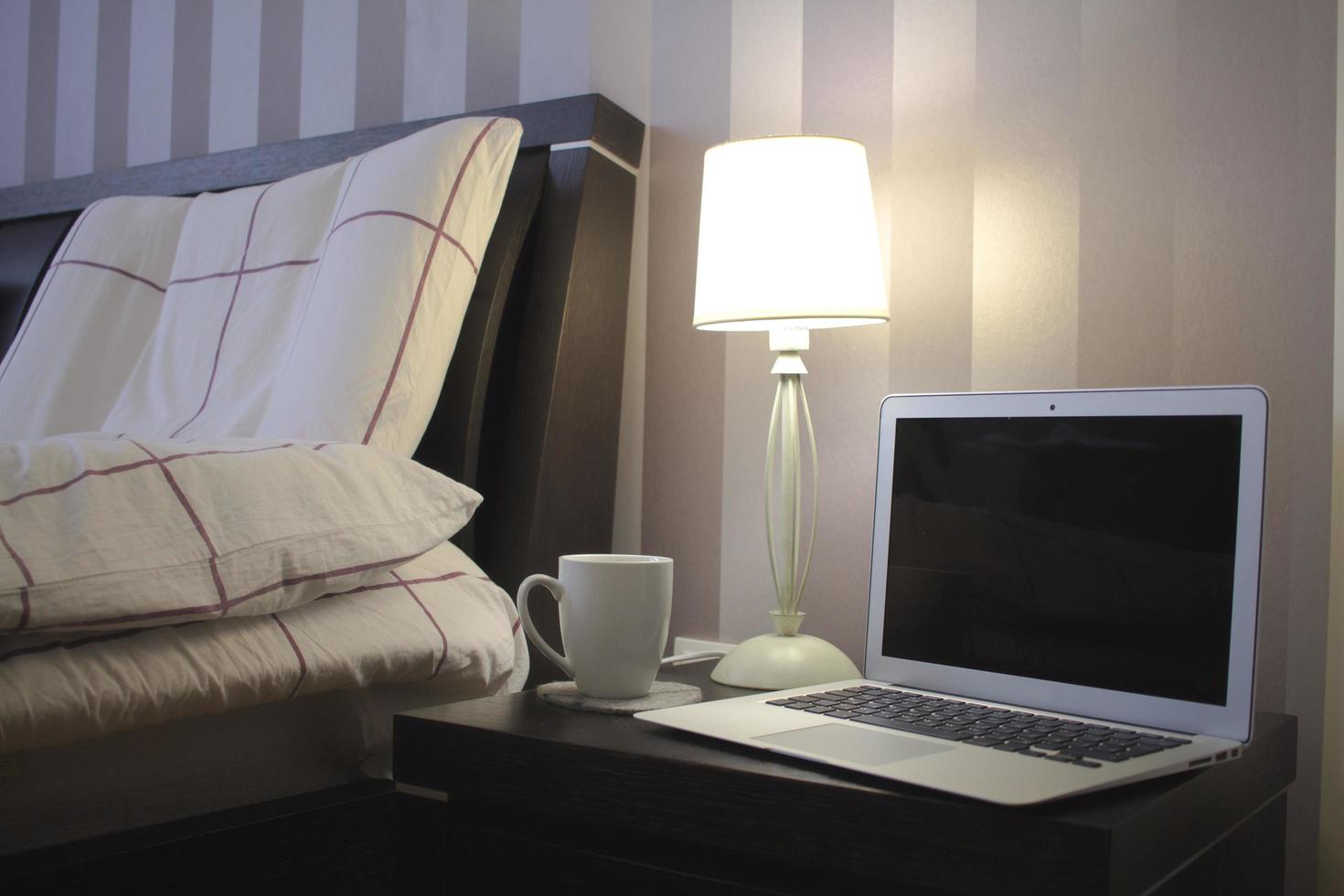 ordinateur portable dans la chambre avec lit, lampe et décor à la maison. photo