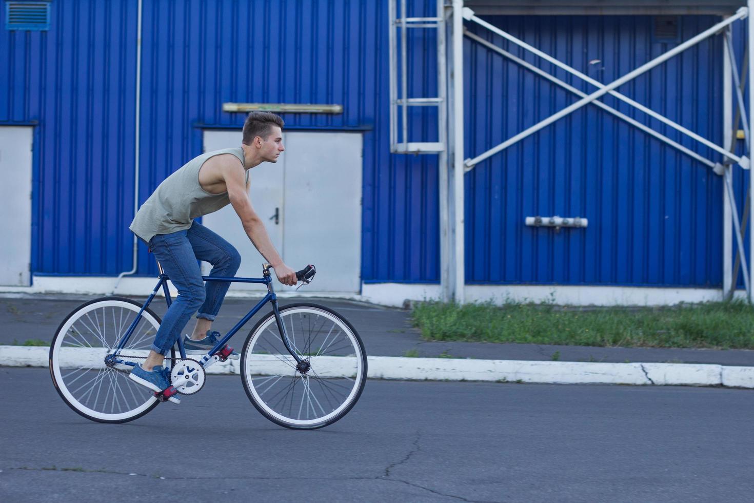 jeune homme marche avec vélo fixie, arrière-plan urbain, photo de hipster avec vélo aux couleurs bleues