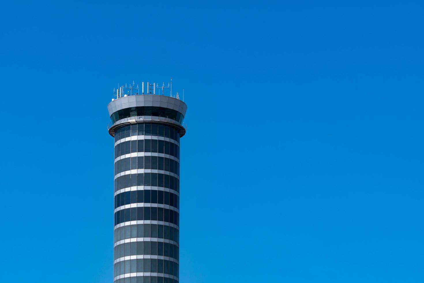 tour de contrôle du trafic aérien à l'aéroport contre le ciel bleu clair. tour de contrôle de l'aéroport pour le contrôle de l'espace aérien par radar. technologie aéronautique. concept de gestion de vol. architecture de verre moderne. photo