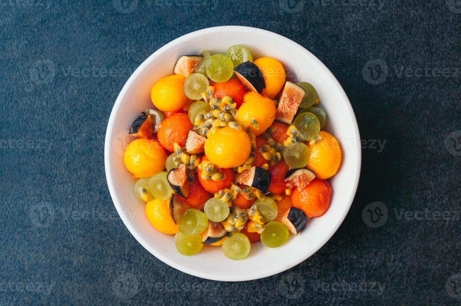 plateau de fruits sains. mise au point sélective. bol de mangue colorée coupée, figues, raisin et papaye sur fond sombre. délicieux plat végétarien. photo