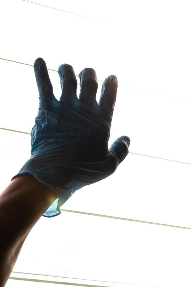 main de silhouette portant des gants bleus avec des persiennes légères. photo