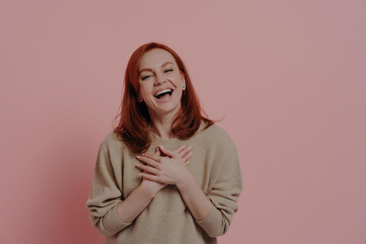 femme drôle aux cheveux roux ravie de rire à haute voix isolée sur fond rose photo