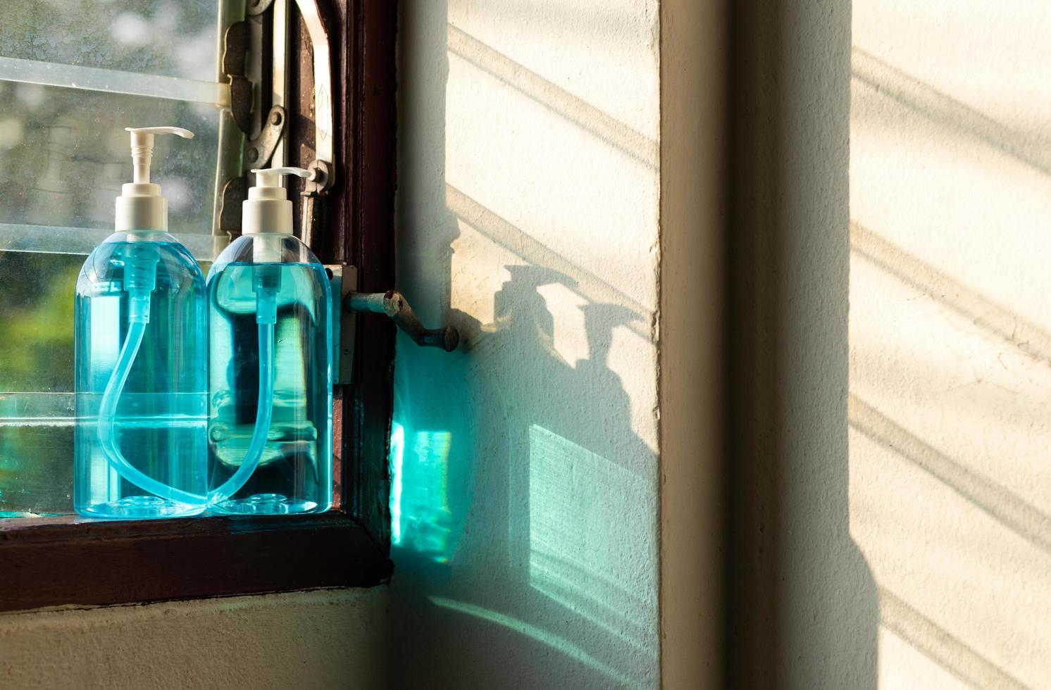 gros plan de deux vaporisateurs d'alcool dans la fenêtre à persiennes. photo