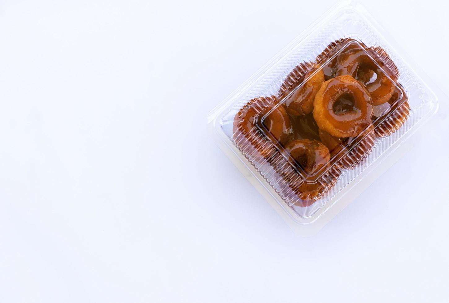 beignets frits de thaïlande, caramel enrobés dans une boîte en plastique transparent sur fond blanc. photo