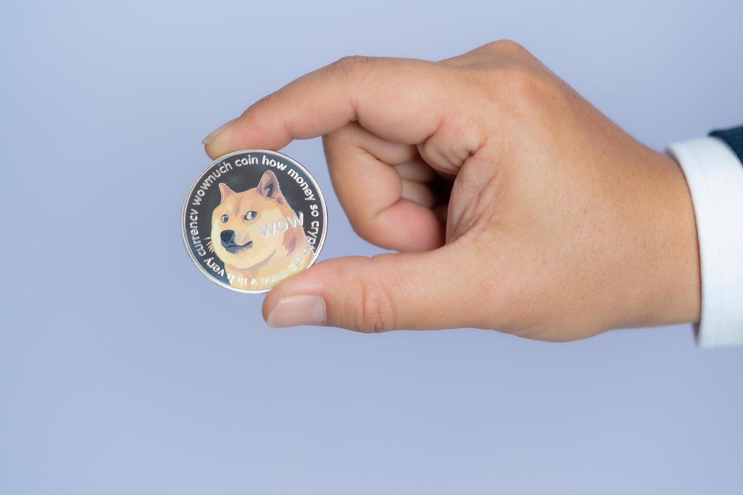 dogecoin doge inclus avec la crypto-monnaie à portée de main homme d'affaires portant un costume bleu. déposé et mis et me donner. photo