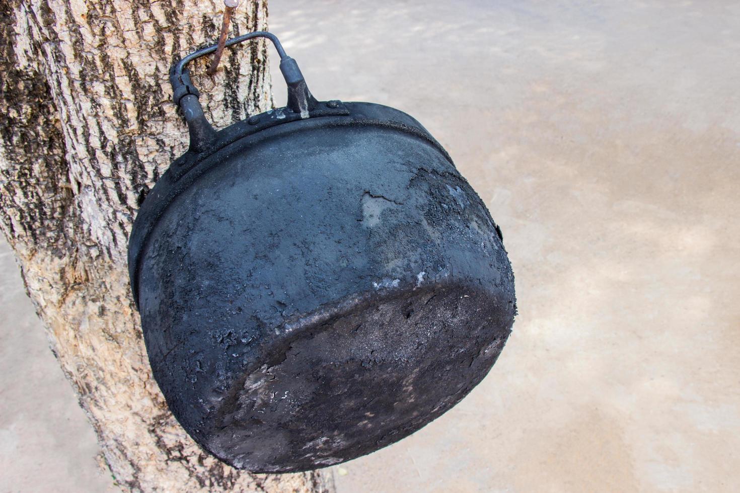 vieux pot noir à travers l'utilisation de la cuisson pendant une longue période accrocher sur l'arbre. photo