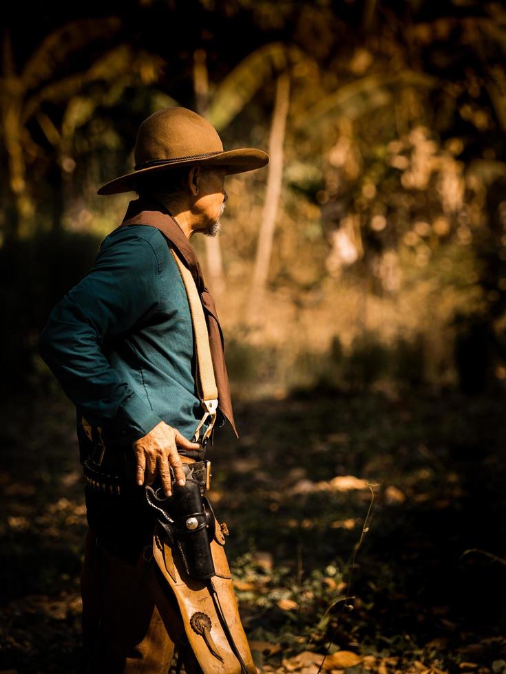 le cow-boy senior se prépare à une fusillade contre des adversaires dans les terres occidentales interdites photo